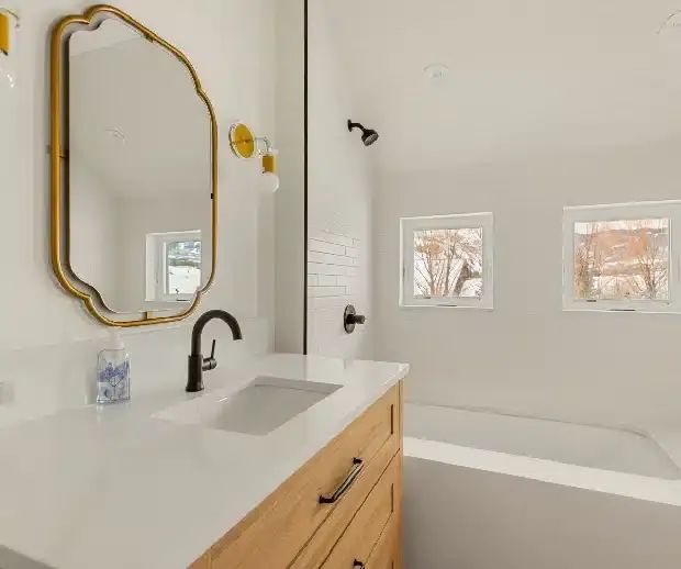 Scalloped brass mirror over a wood vanity