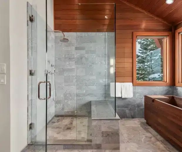 Glass walk-in shower with stone tile under a cedar ceiling