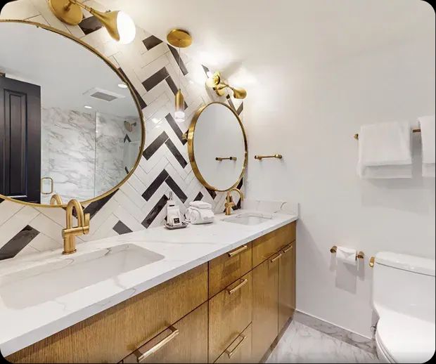 Chevron tile backsplash with brass mirror and wood vanity