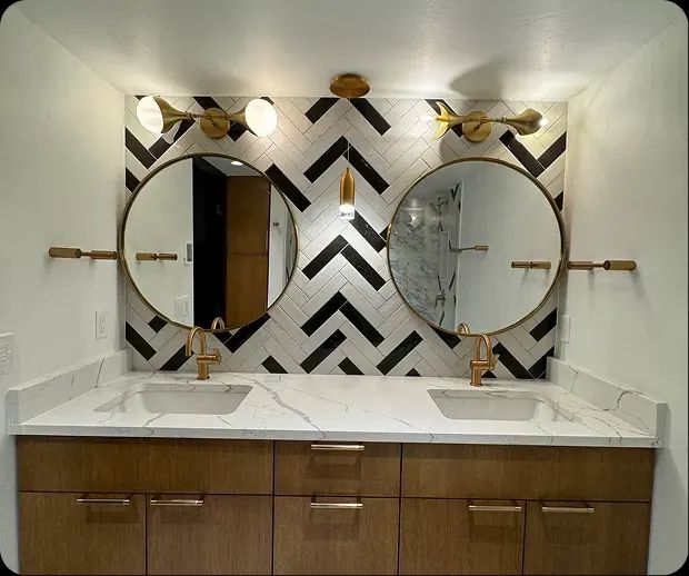 Double vanity with round brass mirrors on chevron tile