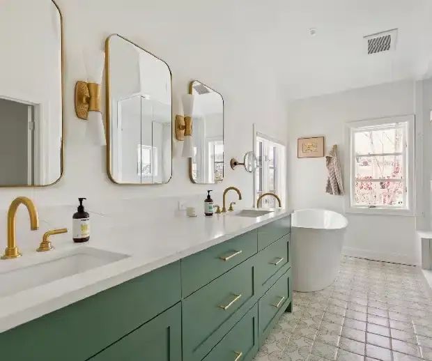 Green vanity with brass mirrors and freestanding tub