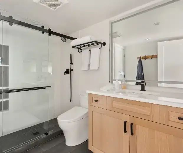 Oak vanity beside a glass shower with sliding door