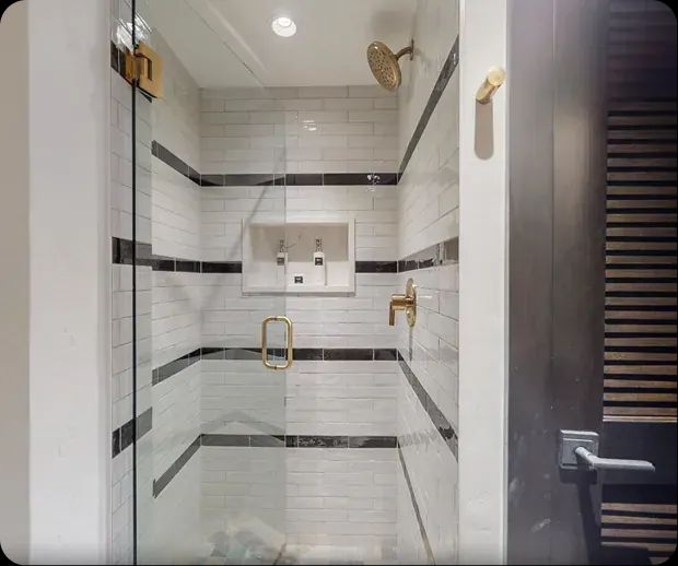 Walk-in shower with striped tile and brass hardware