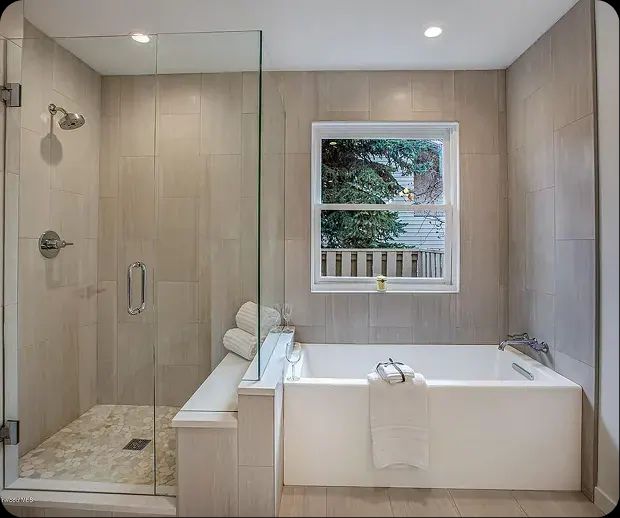 Tiled walk-in shower and soaking tub under a window