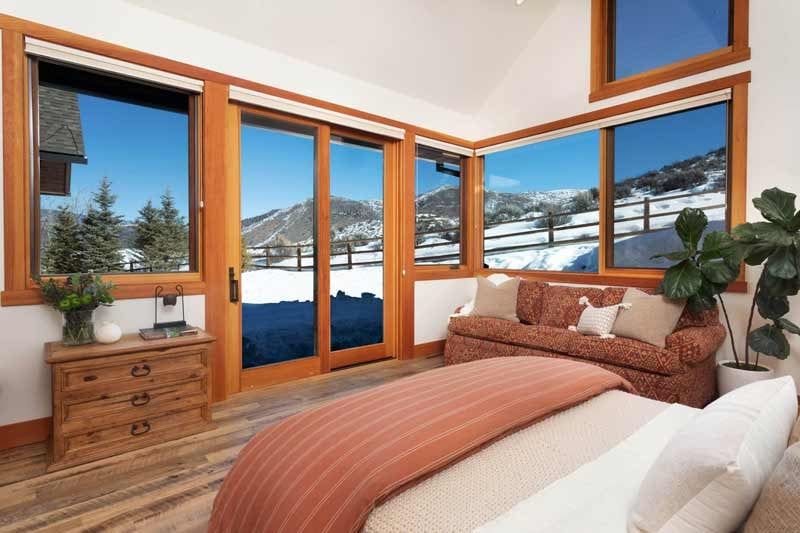 Custom home bedroom with large corner windows overlooking snowy hills
