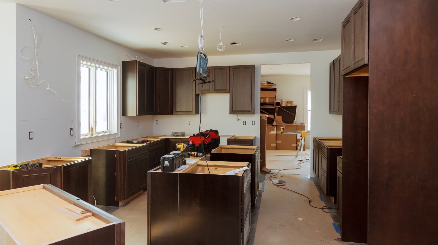 Kitchen remodel in progress with dark wood cabinets installed and tools on the base units