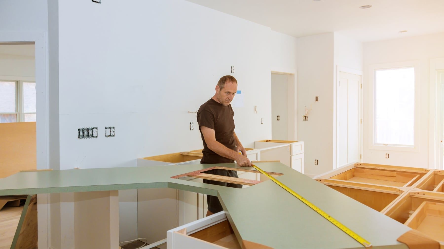 Installer measuring a countertop template on new kitchen base cabinets