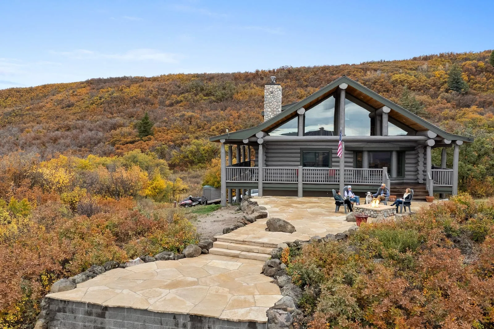 Log home with a new flagstone patio and stone steps on an autumn hillside