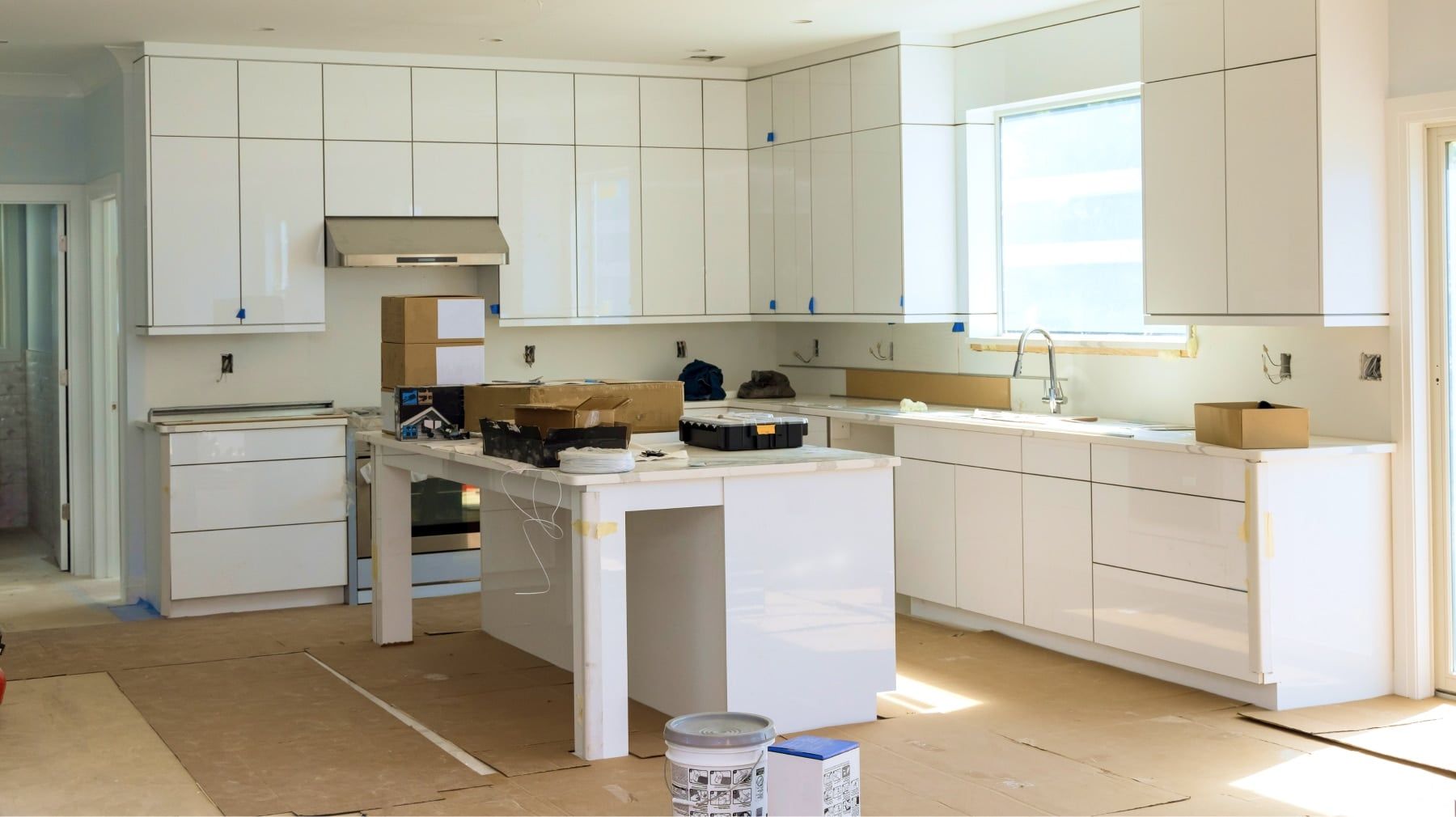 Kitchen remodel in progress with glossy white cabinets installed and countertops still to come