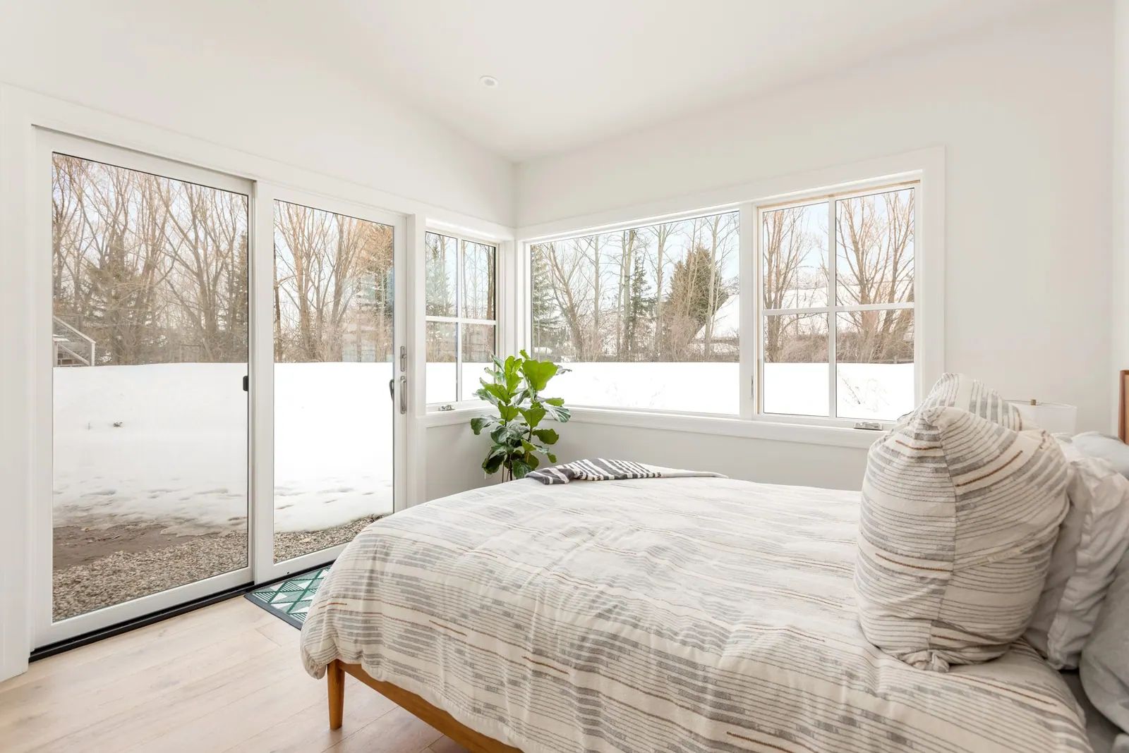 Bright bedroom with corner windows overlooking a snowy yard