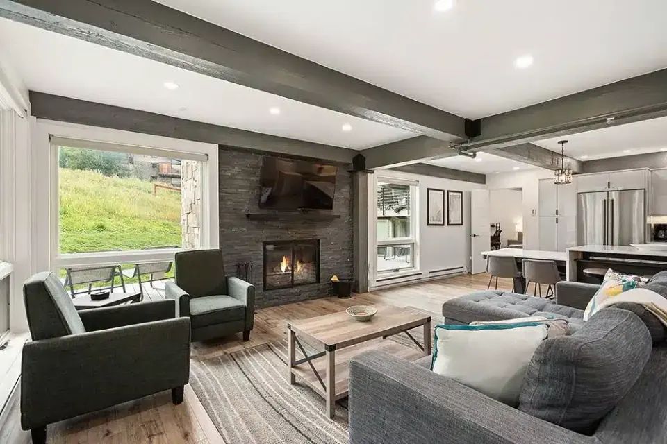 Remodeled living room with stone fireplace open to a modern kitchen