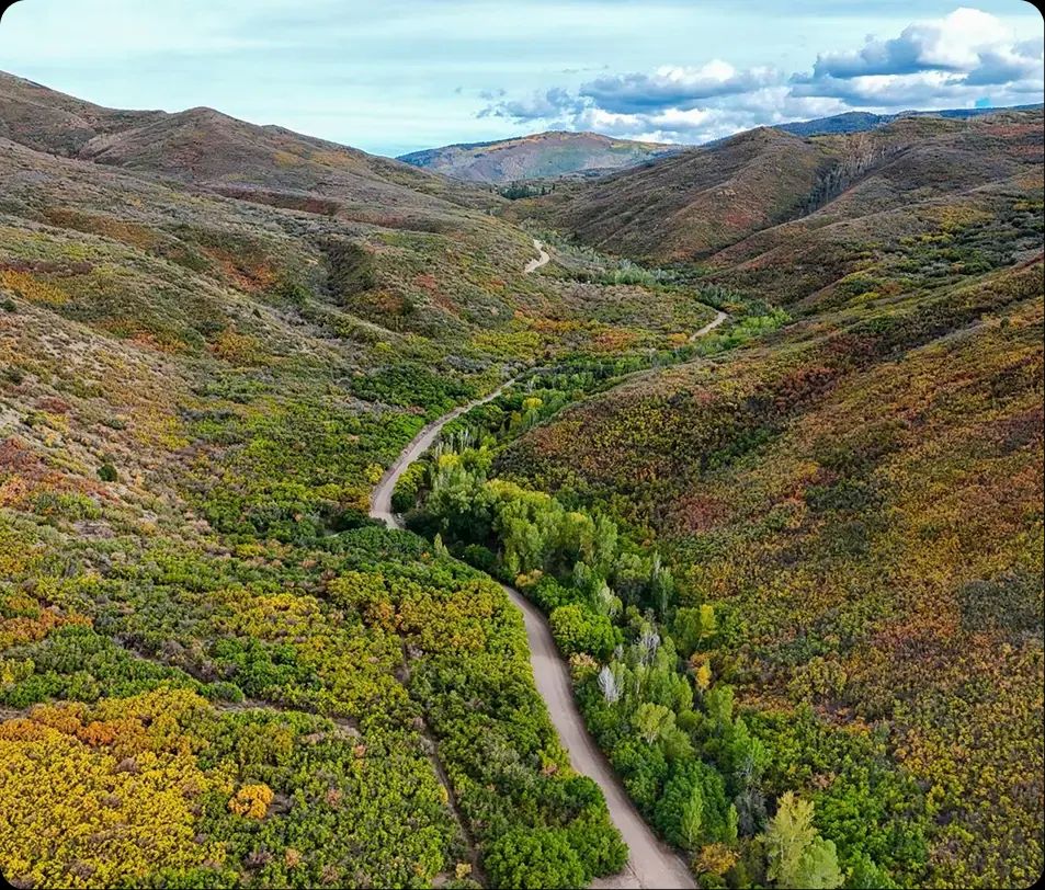 Aerial view of a road winding through an autumn mountain valley