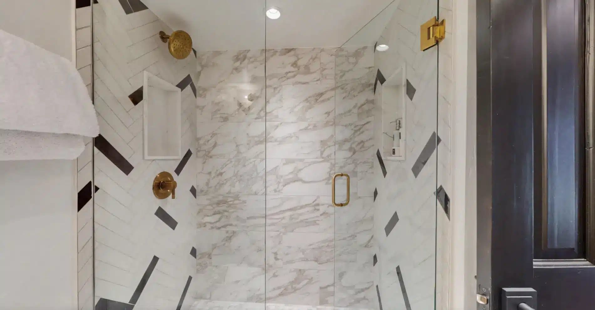Walk-in shower with herringbone tile and brass fixtures