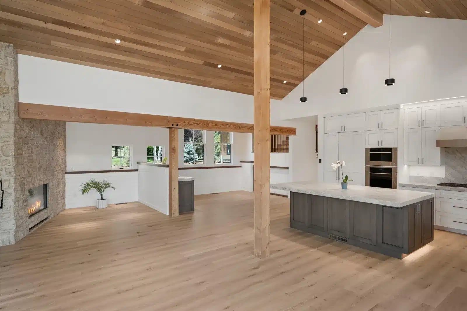 Great room at 114 Crystal Canyon with a timber post, stone fireplace and kitchen island under a vaulted wood ceiling