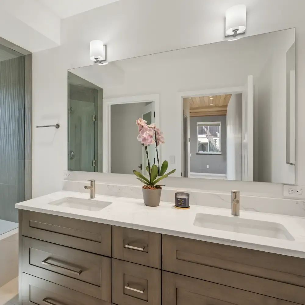 Bright bathroom with a double vanity, wide mirror and an orchid