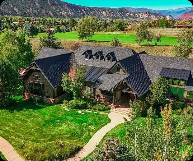 Aerial view of a dark-roofed mountain home and lawn