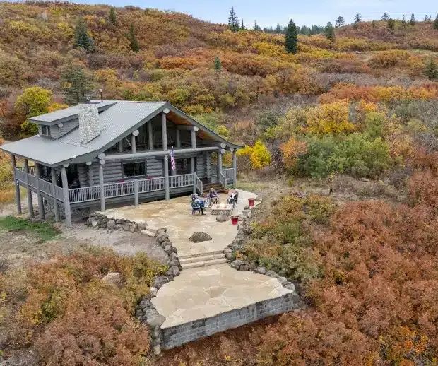Aerial view of a mountain cabin and stone patio in autumn