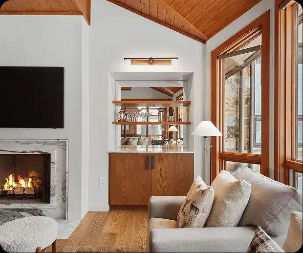 Marble fireplace beside a built-in bar under a cedar ceiling