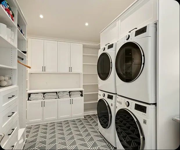 Laundry room with stacked washers and dryers and white cabinetry