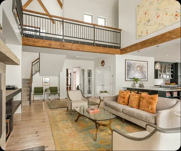 Living room with loft railing, orange pillows and patterned rug