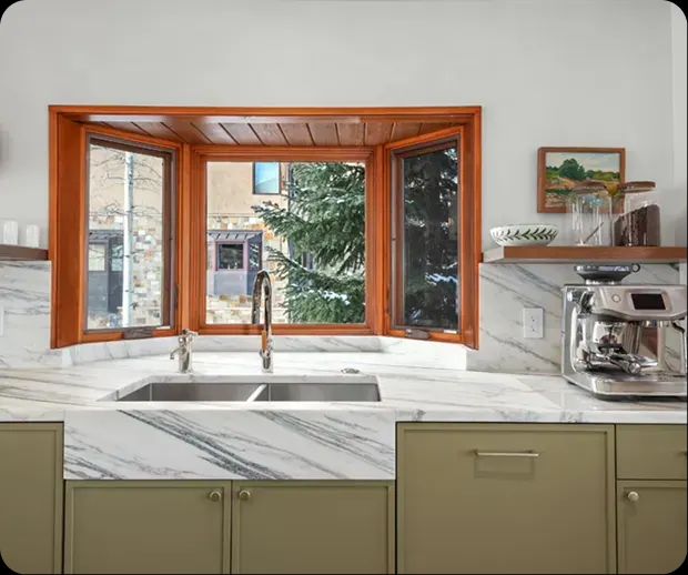 Bay window sink with marble counters and wood trim