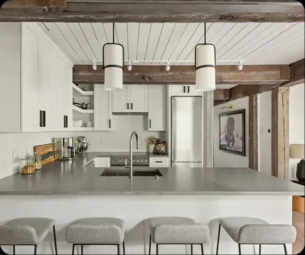 Kitchen with gray island, white pendants and plank ceiling