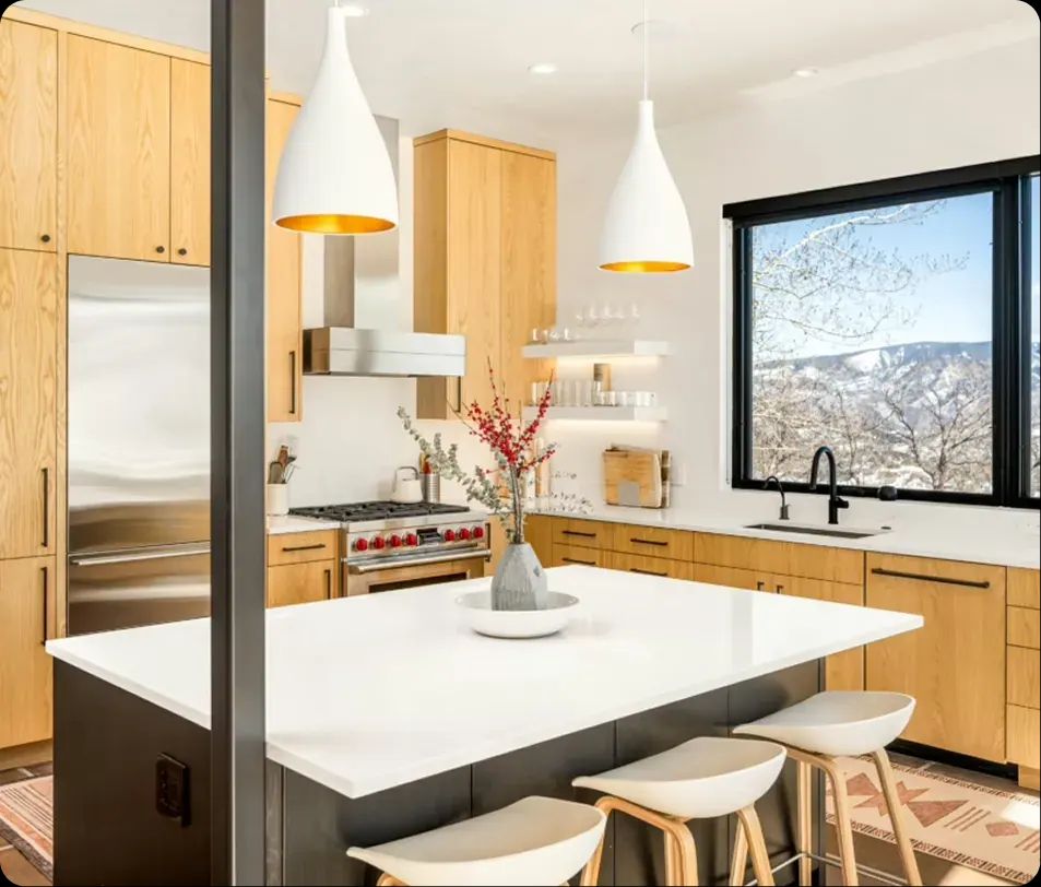 Light oak kitchen with white pendants, island seating and a mountain view