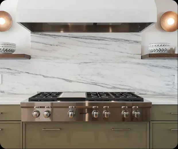 Marble slab backsplash behind a professional gas range