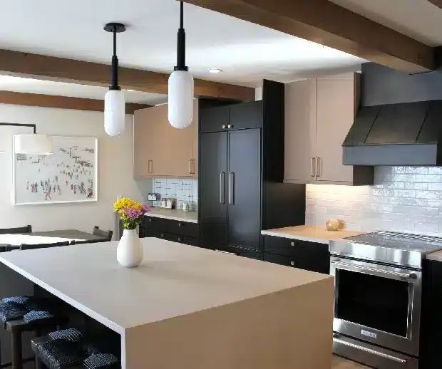 Kitchen with waterfall island, black cabinetry and pendant lights