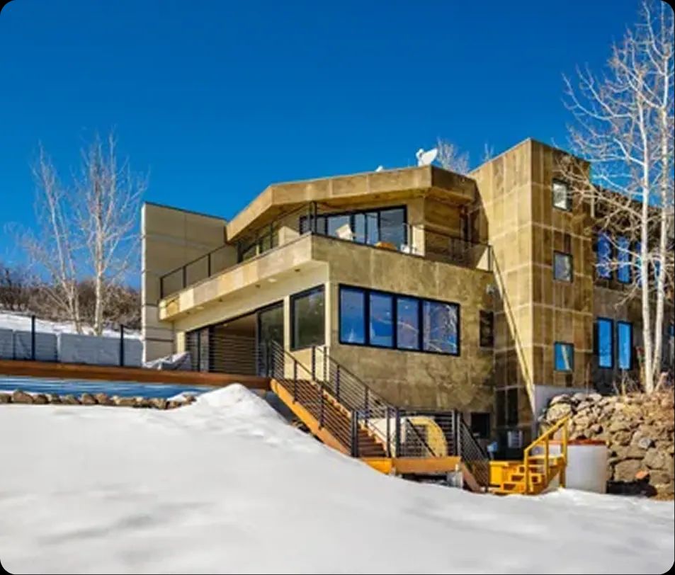 Modern custom home with steel balconies surrounded by winter snow