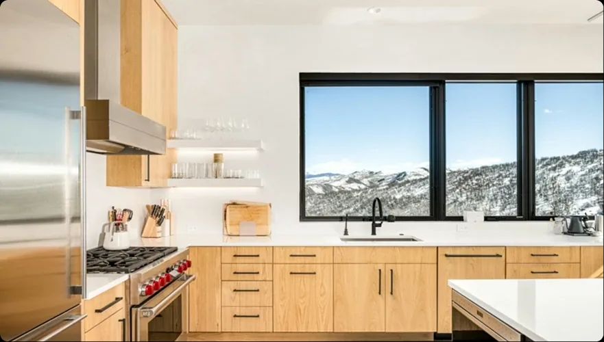 Light wood kitchen with a picture window to snowy mountains