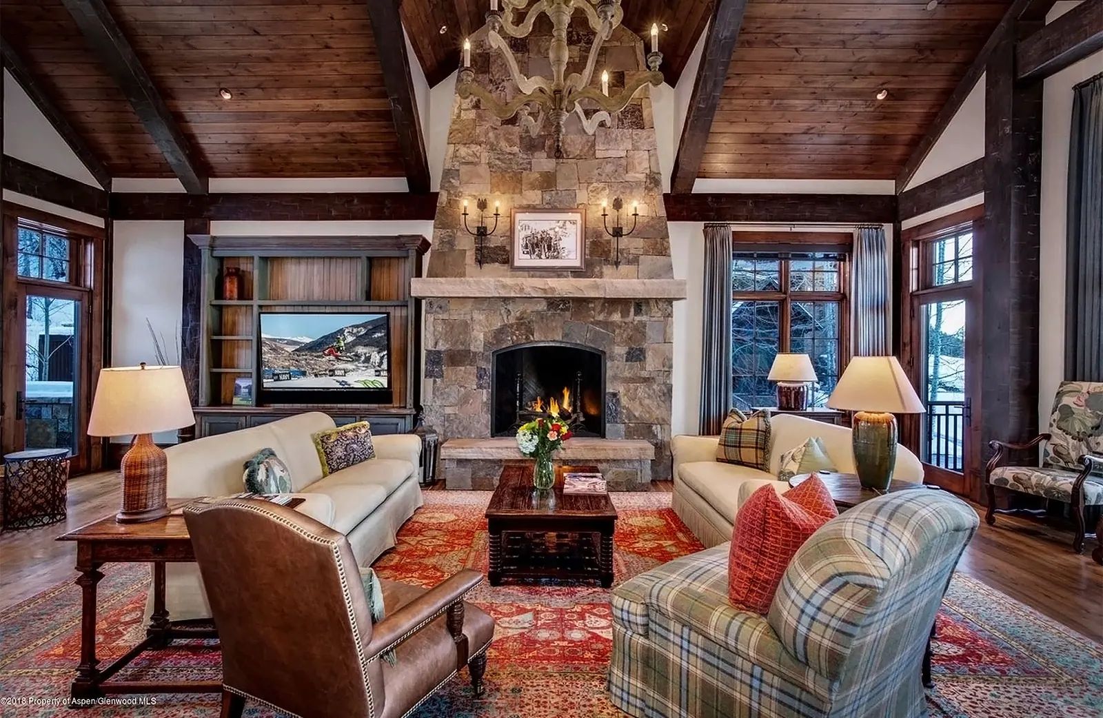 Mountain home living room with a stone fireplace and timber ceiling