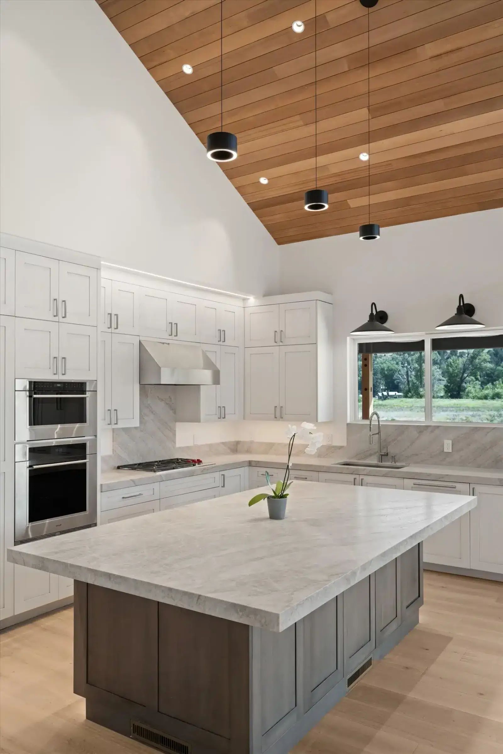 White kitchen with large island under a vaulted wood ceiling