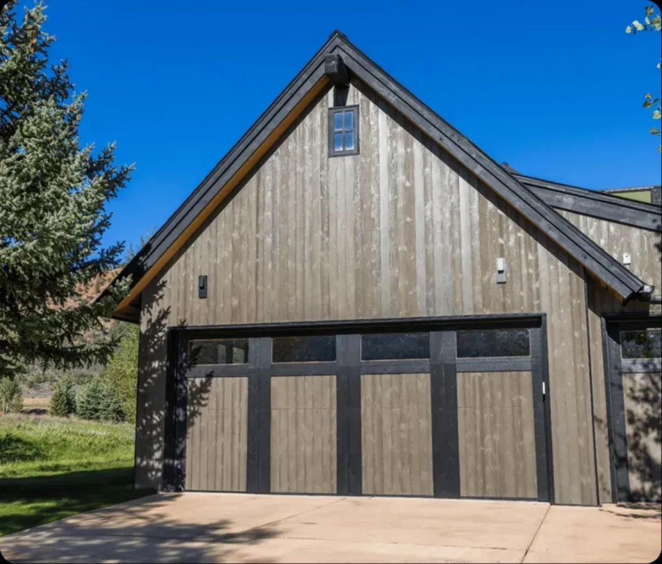 Mountain home garage with weathered wood siding and black-trimmed doors